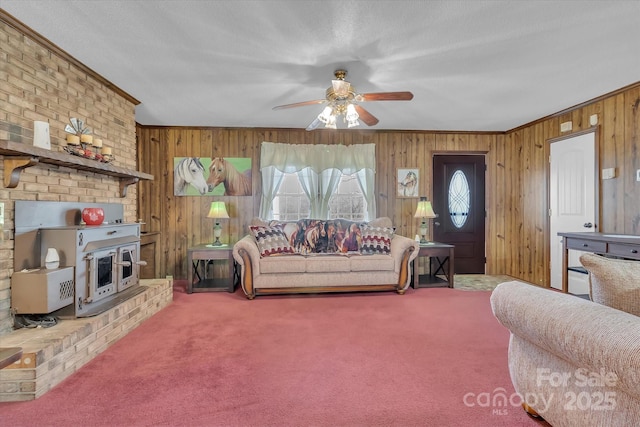 carpeted living room with wooden walls, ornamental molding, and ceiling fan