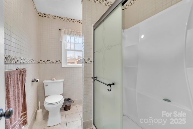 bathroom with walk in shower, tile patterned floors, toilet, and tile walls