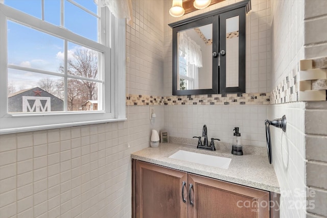 bathroom with tasteful backsplash, a healthy amount of sunlight, vanity, and tile walls