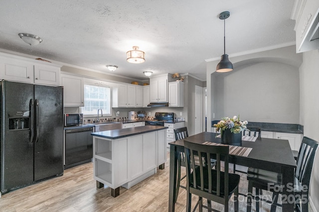 kitchen featuring sink, white cabinetry, hanging light fixtures, black appliances, and light wood-type flooring