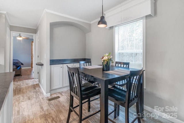 dining space with crown molding, ceiling fan, and light hardwood / wood-style flooring