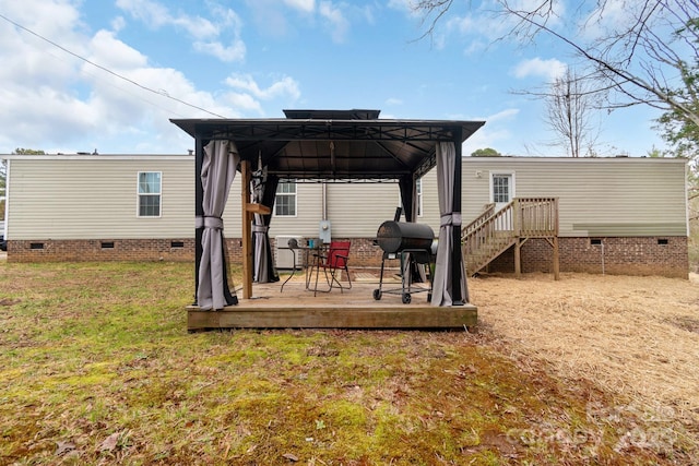 rear view of house with a gazebo, a deck, and a lawn