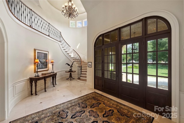 foyer with a high ceiling, a wealth of natural light, an inviting chandelier, and french doors