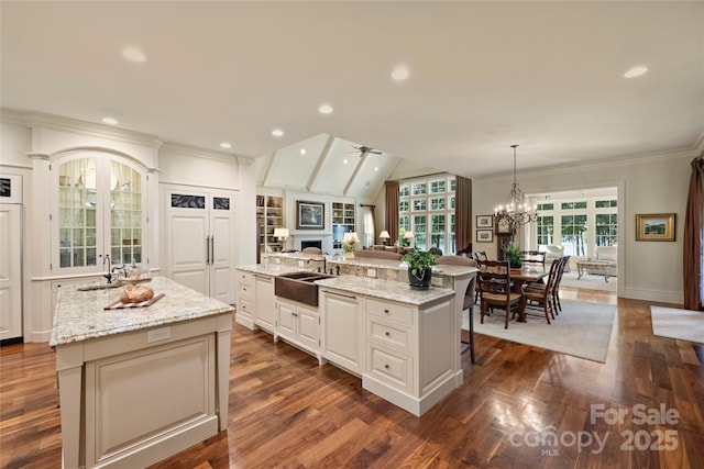 kitchen with sink, a breakfast bar area, white cabinetry, hanging light fixtures, and a kitchen island