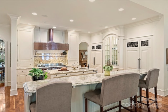 kitchen featuring a large island, backsplash, light stone counters, a kitchen bar, and dark hardwood / wood-style flooring