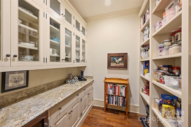 interior space with crown molding, dark wood-type flooring, light stone countertops, and white cabinets