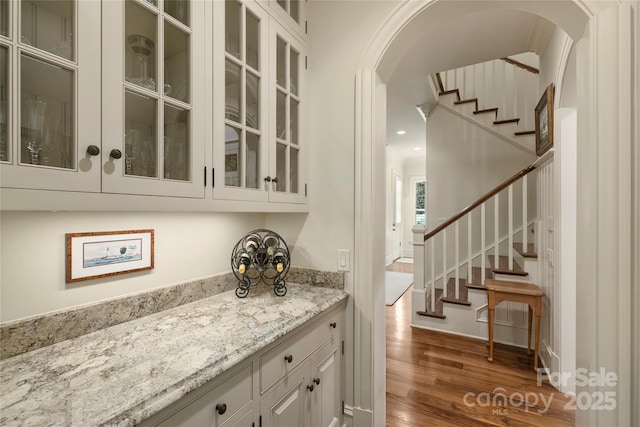 bar with white cabinetry, light stone countertops, and dark hardwood / wood-style floors