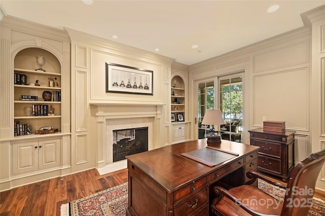 office featuring a multi sided fireplace, dark wood-type flooring, ornamental molding, and built in shelves