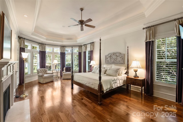 bedroom with hardwood / wood-style flooring, ceiling fan, a tray ceiling, and crown molding