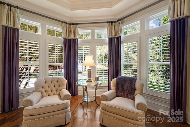 living area featuring hardwood / wood-style floors, ornamental molding, and a raised ceiling