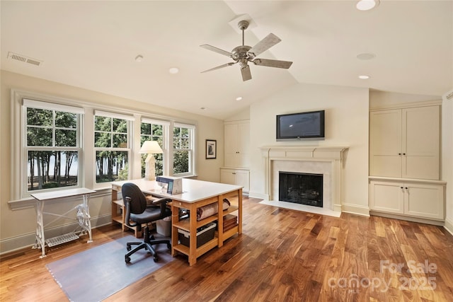 office space featuring ceiling fan, a fireplace, vaulted ceiling, and light hardwood / wood-style flooring