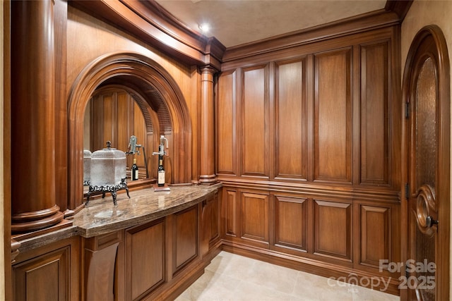 bar with ornate columns, wood walls, and stone counters