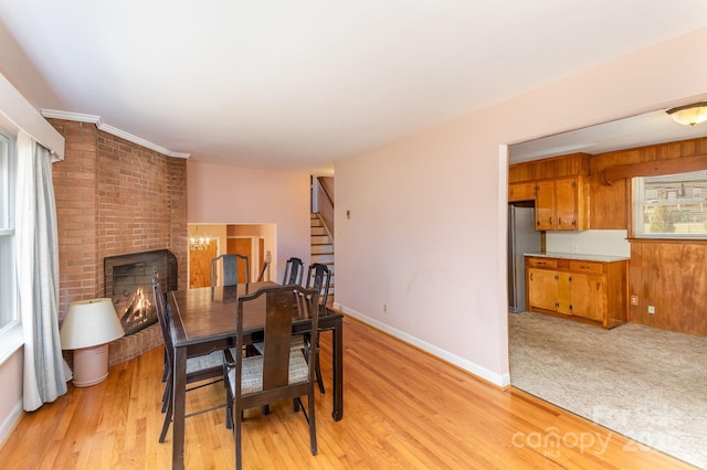 dining room featuring a brick fireplace and light hardwood / wood-style flooring