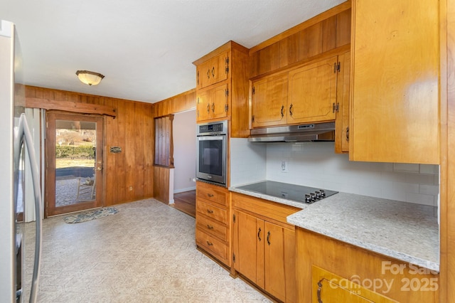 kitchen featuring stainless steel appliances, wooden walls, and decorative backsplash