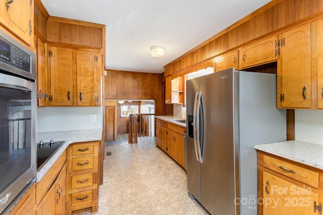 kitchen featuring decorative backsplash, wooden walls, and stainless steel appliances