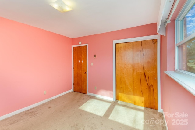 unfurnished bedroom featuring light colored carpet and a closet