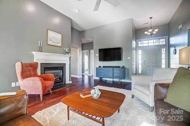 living room with high vaulted ceiling, ceiling fan with notable chandelier, and dark hardwood / wood-style flooring