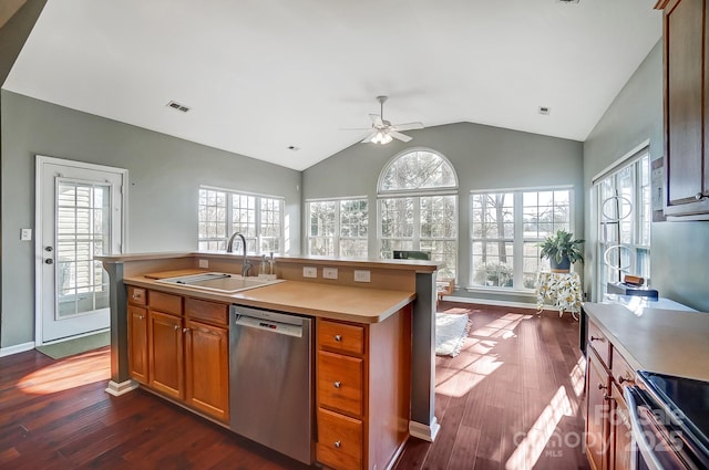 kitchen with sink, appliances with stainless steel finishes, dark hardwood / wood-style flooring, a healthy amount of sunlight, and a kitchen island with sink