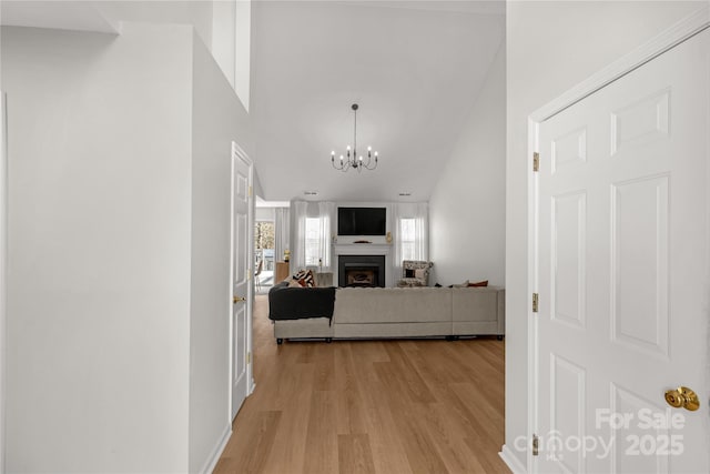 hallway featuring a high ceiling, an inviting chandelier, and light hardwood / wood-style flooring