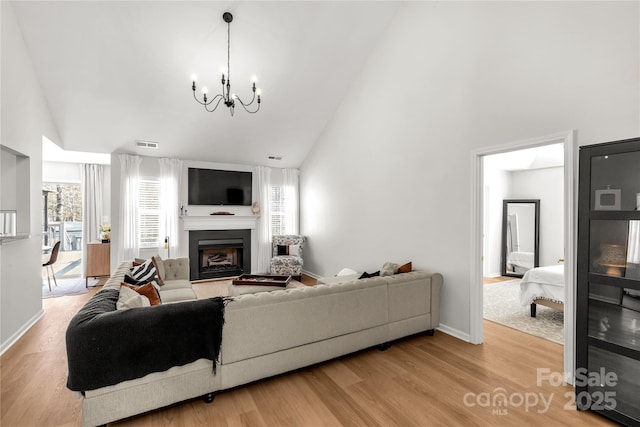 living room with hardwood / wood-style flooring, high vaulted ceiling, and a notable chandelier