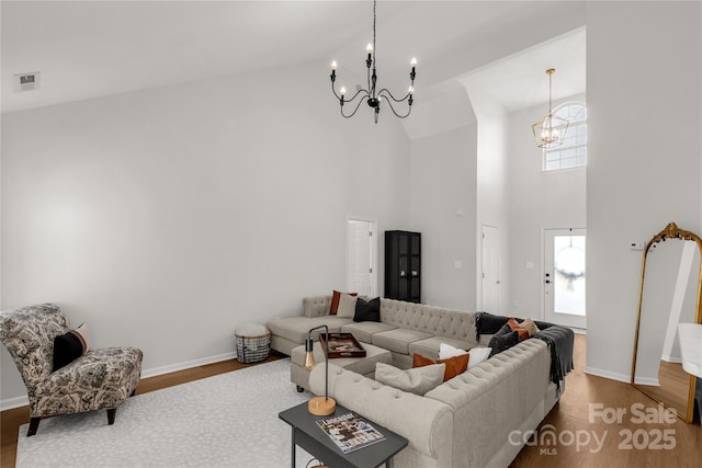 living room with hardwood / wood-style flooring, high vaulted ceiling, an inviting chandelier, and a wealth of natural light