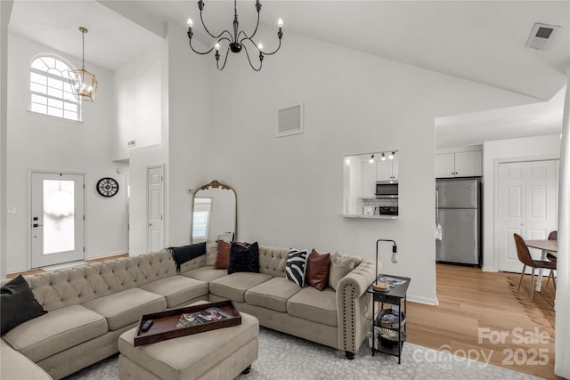 living room featuring vaulted ceiling, light wood-type flooring, and an inviting chandelier