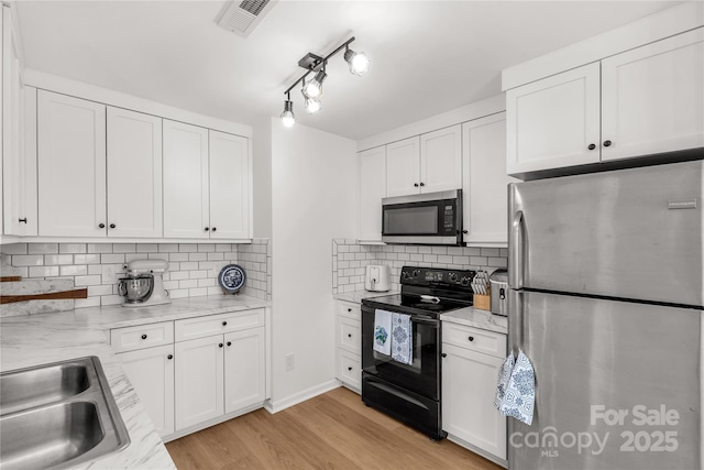 kitchen with white cabinetry, appliances with stainless steel finishes, and light hardwood / wood-style floors