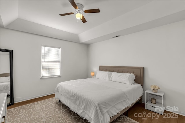 bedroom featuring a raised ceiling, hardwood / wood-style floors, and ceiling fan