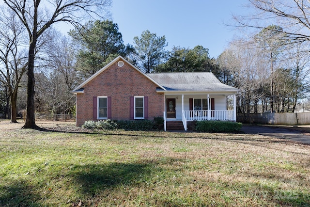 ranch-style house featuring covered porch and a front lawn