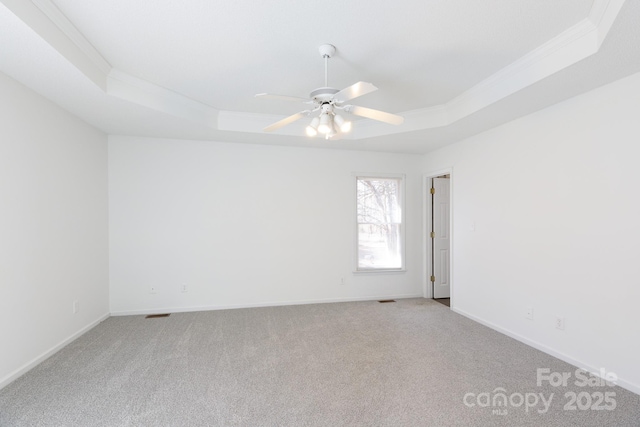 carpeted spare room with crown molding, a raised ceiling, and ceiling fan