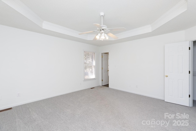 spare room with ornamental molding, light carpet, ceiling fan, and a tray ceiling