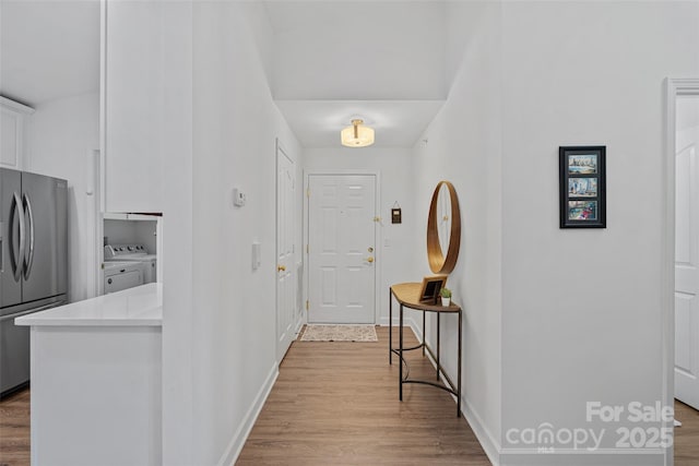 foyer with washer and clothes dryer and light wood-type flooring