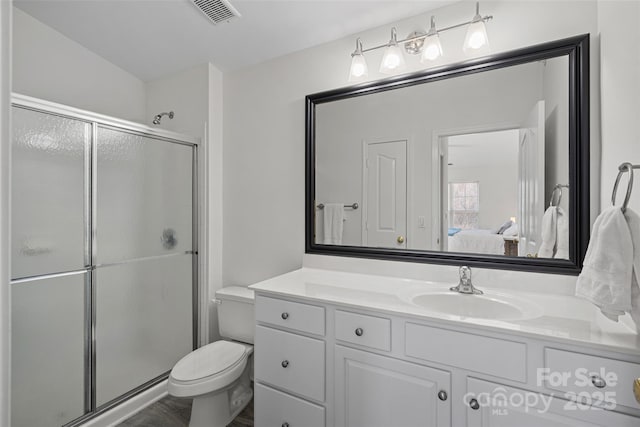 bathroom featuring vanity, toilet, and a shower with shower door