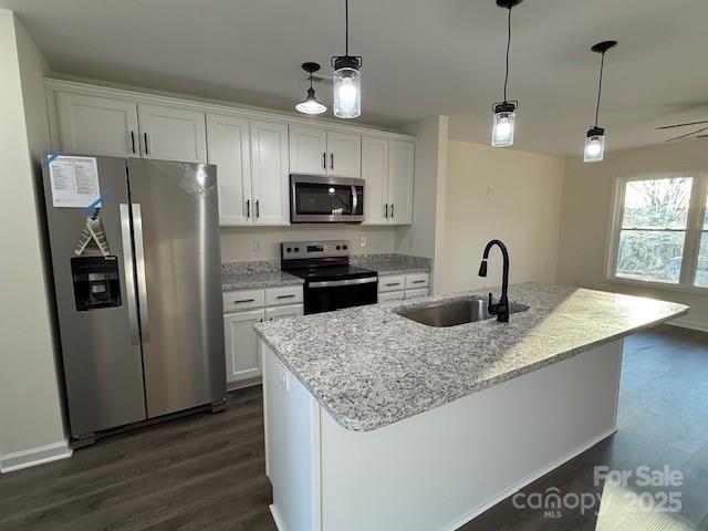 kitchen with white cabinetry, stainless steel appliances, a kitchen island with sink, and sink