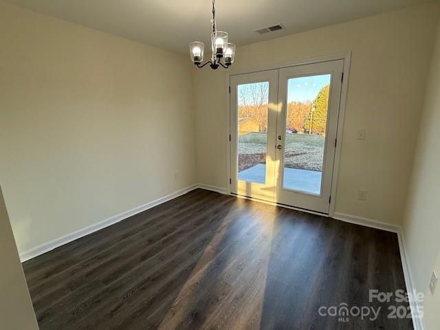 unfurnished room featuring dark hardwood / wood-style floors, a chandelier, and french doors