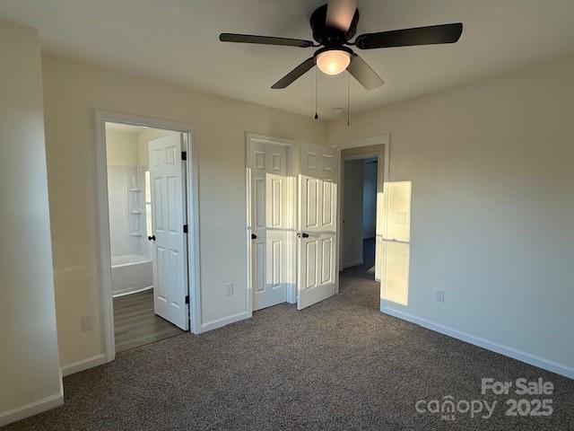 unfurnished bedroom with connected bathroom, ceiling fan, and dark colored carpet