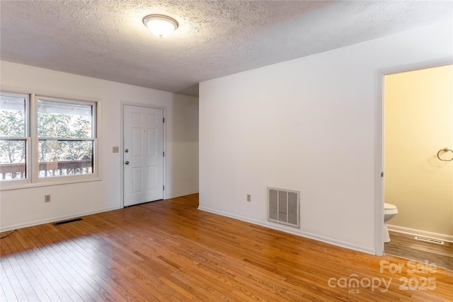 empty room featuring a textured ceiling and light hardwood / wood-style flooring