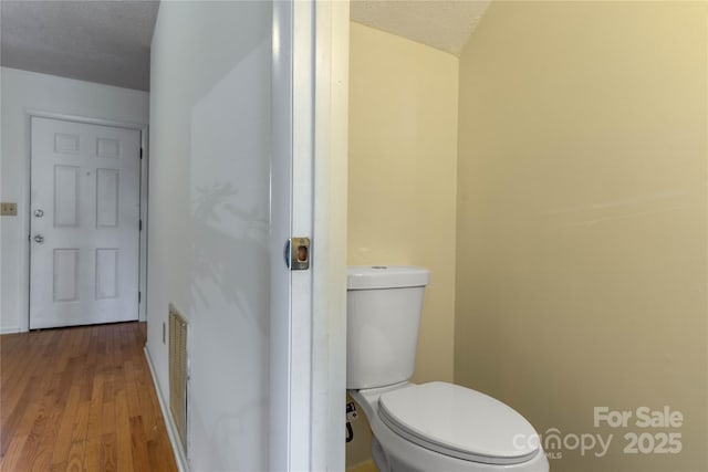 bathroom featuring hardwood / wood-style floors, a textured ceiling, and toilet