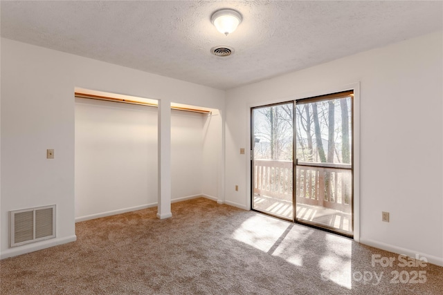 unfurnished bedroom with multiple closets, access to outside, light carpet, and a textured ceiling