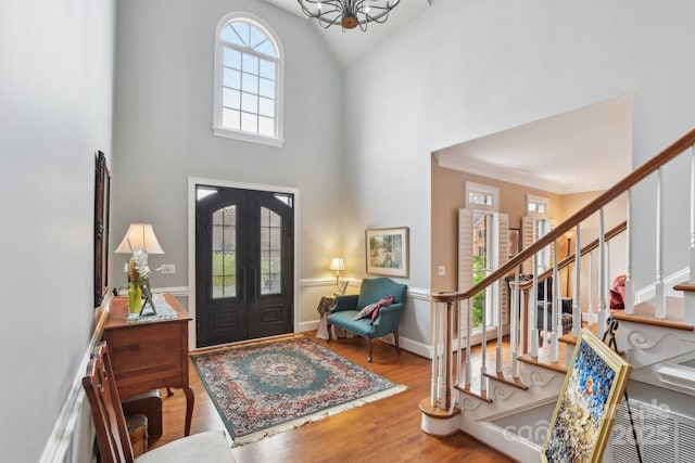 foyer with a chandelier, french doors, a high ceiling, and light wood-type flooring