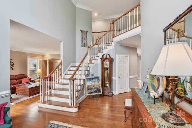 staircase featuring hardwood / wood-style flooring, crown molding, and a towering ceiling