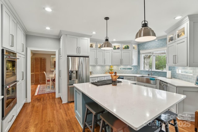 kitchen with hanging light fixtures, stainless steel appliances, a center island, and a kitchen bar