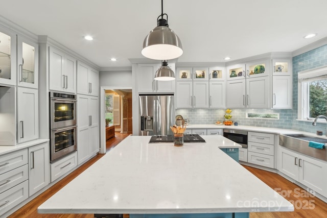 kitchen featuring a large island, hanging light fixtures, stainless steel appliances, and sink