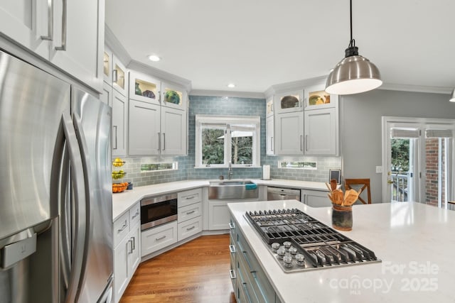 kitchen with ornamental molding, stainless steel appliances, hanging light fixtures, and white cabinets