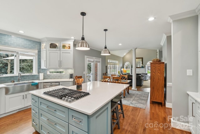 kitchen featuring pendant lighting, sink, appliances with stainless steel finishes, white cabinetry, and a kitchen island