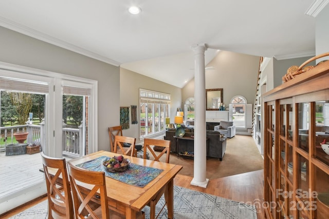 dining space with lofted ceiling, crown molding, decorative columns, and light hardwood / wood-style floors