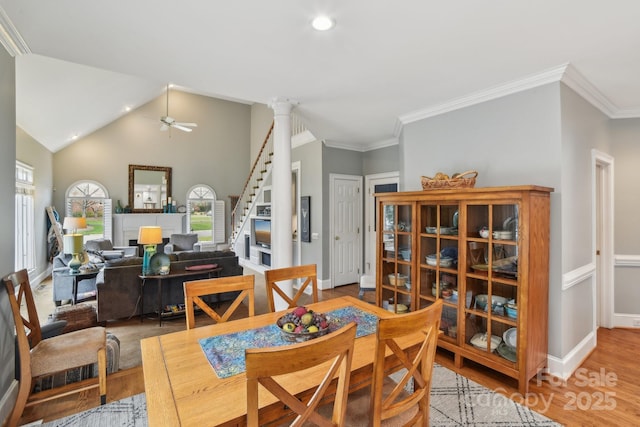 dining room featuring ornate columns, wood-type flooring, vaulted ceiling, and crown molding