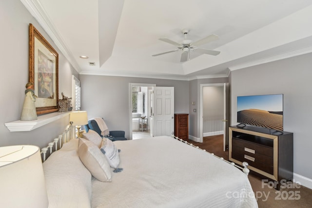 bedroom with crown molding, ceiling fan, connected bathroom, a tray ceiling, and dark carpet