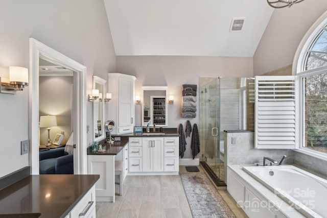 bathroom with vanity, hardwood / wood-style flooring, vaulted ceiling, and plus walk in shower