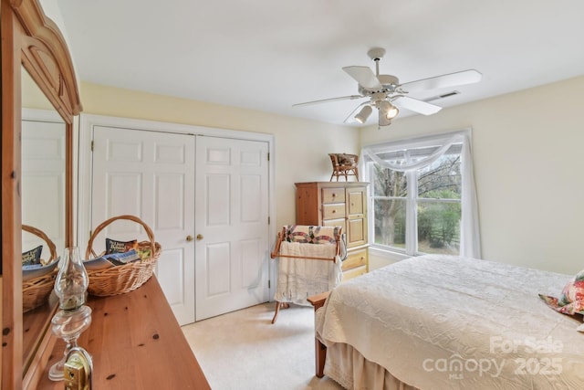 bedroom with light colored carpet, ceiling fan, and a closet